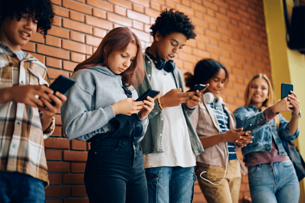 Multiracial group of teenagers using their cell phones at high school.